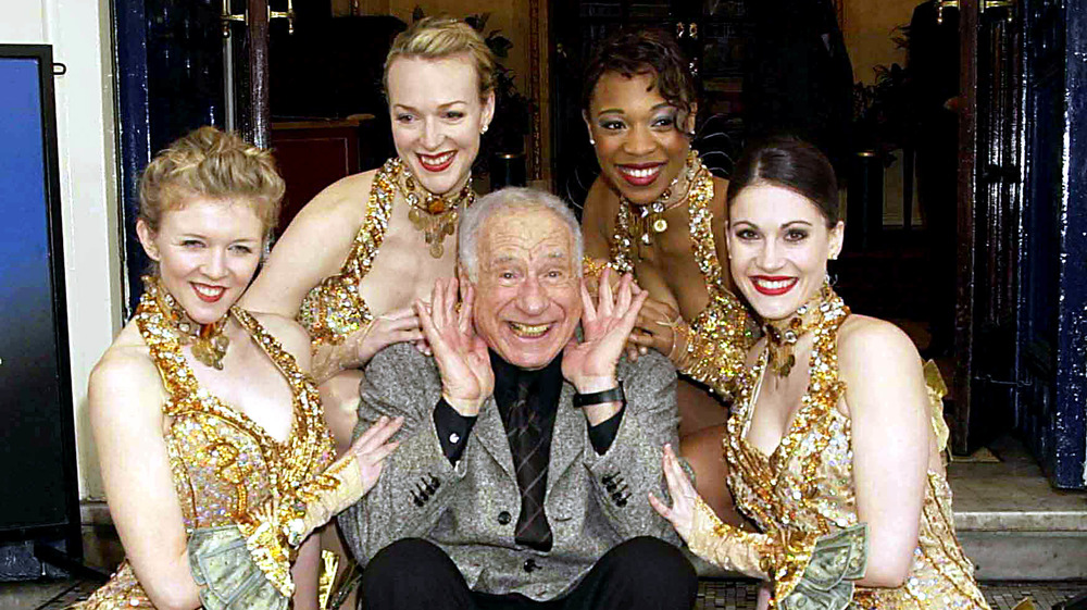 Mel Brooks smiling with show girls